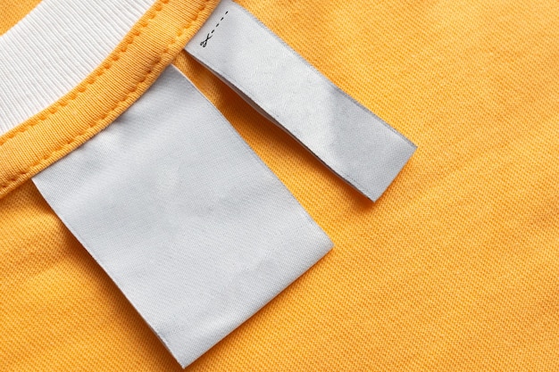 Foto leeres weißes wäschepflegeetikett auf gelbem stofftexturhintergrund