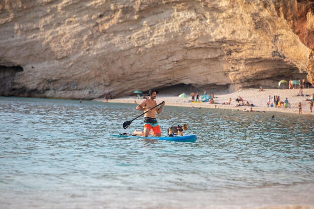 Lefkada Grecia 7 de septiembre de 2021 hombre paddle surf con perro vacaciones en el mar