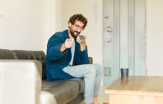 Foto legal jovem sentado em um sofá na sala assistindo tv