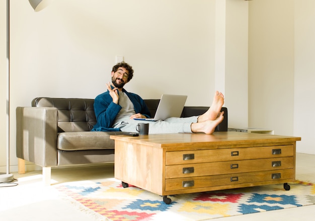 Legal jovem sentado em um sofá na sala assistindo tv