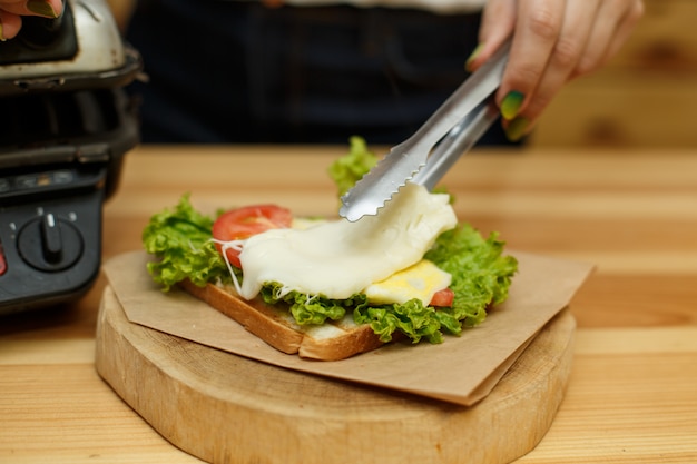 Legen Sie den geschmolzenen Käse in ein Sandwich. kochen saftiges sandwich