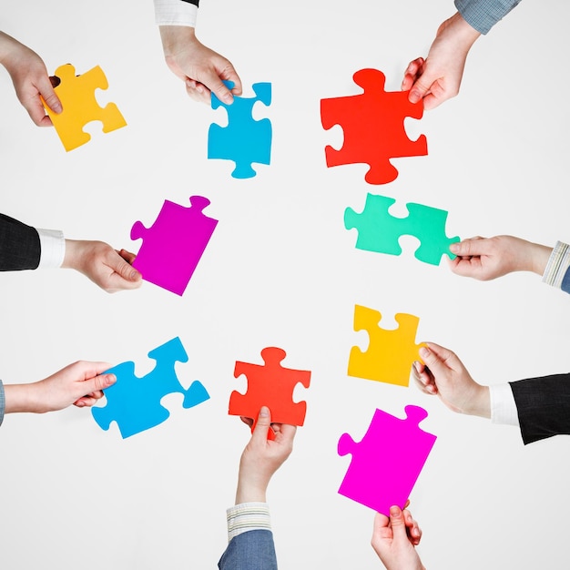 Legen Sie Puzzleteile in die Hände der Menschen im Kreis