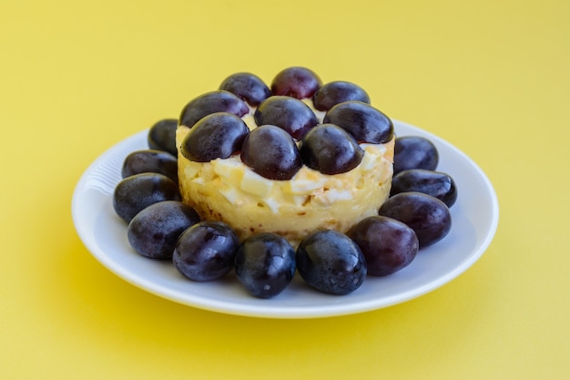 La legendaria ensalada Tiffany en capas con uvas, pollo y queso sobre fondo amarillo. Recibió su nombre del apodo de la señora que publicó la receta de la ensalada en el portal culinario.