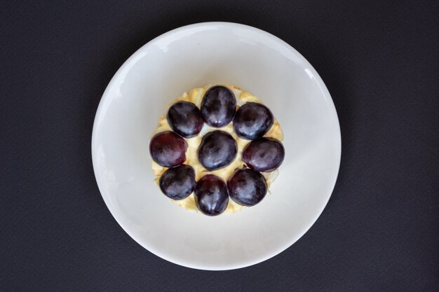 La legendaria ensalada Tiffany en capas con uvas, pollo y queso sobre fondo negro. Recibió su nombre del apodo de la señora que publicó la receta de la ensalada en el portal culinario.