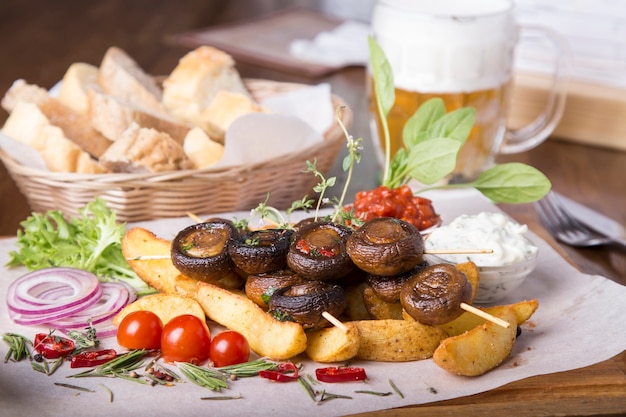 Legumes apetitosos cozidos na grelha. Cogumelos e batatas grelhados. Lanche saboroso