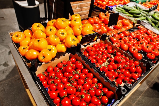 Legumes de tomates vermelhos e amarelos em caixas no supermercado