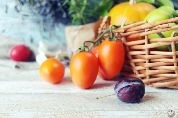 Legumes e frutas em uma cesta de ervas picantes em uma mesa de madeira conceito de colheita de outono