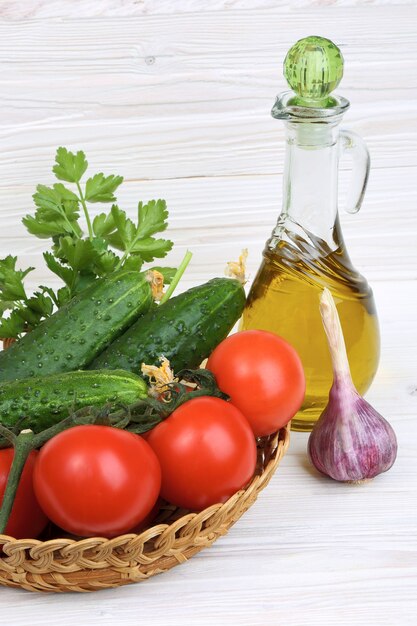 Legumes e uma garrafa de azeite em um fundo claro de madeira