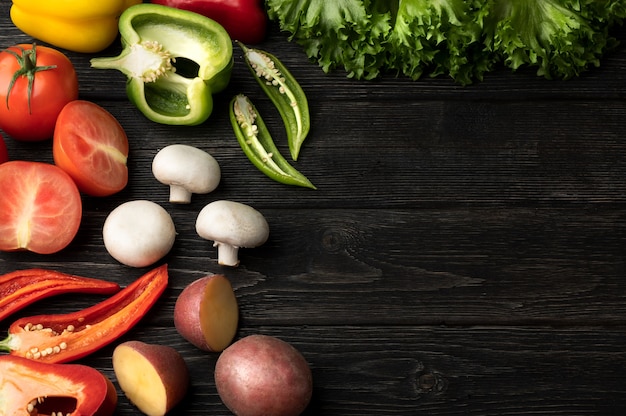 Legumes em uma mesa de madeira preta. Vista superior com espaço de cópia