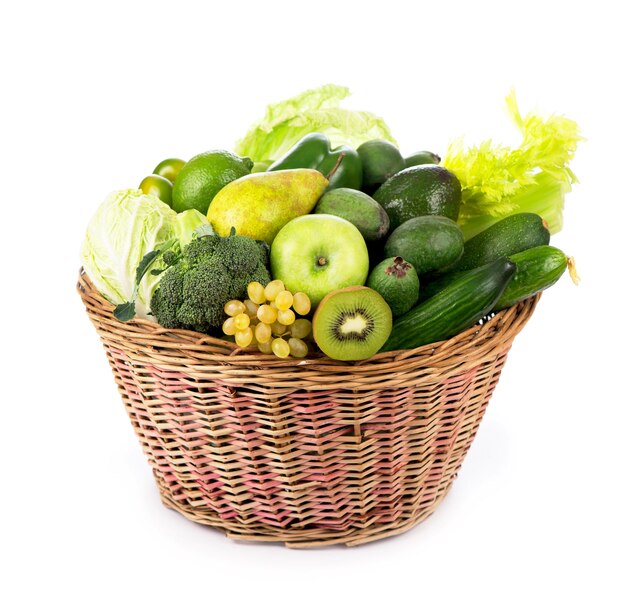 Legumes frescos com folhas kiwi uvas maçãs e colisões pepinos abobrinha brócolis repolho e verduras na cesta isolada no fundo branco