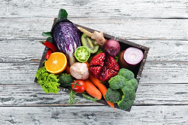 Legumes frescos e frutas em uma caixa de madeira em um fundo branco de madeira Alimentos orgânicos Vista superior Espaço para cópia grátis