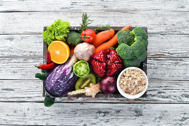 Legumes frescos e frutas em uma caixa de madeira em um fundo branco de madeira Alimentos orgânicos Vista superior Espaço para cópia grátis