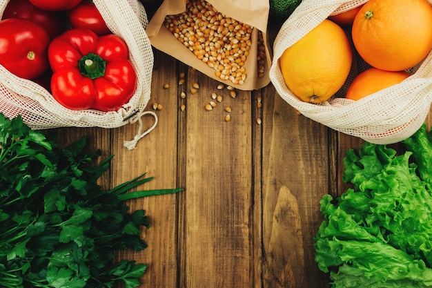 Legumes frescos em sacos ecológicos na mesa de madeira