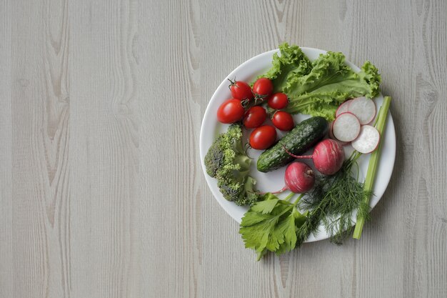 Legumes frescos em um prato branco sobre uma mesa de madeira leve