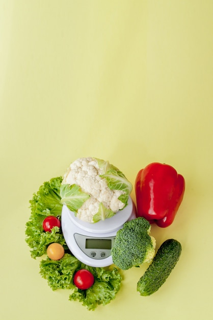 Legumes frescos em um vaso em fundo amarelo. Alimentação saudável, planejamento de dieta, perda de peso, desintoxicação, conceito de agricultura orgânica