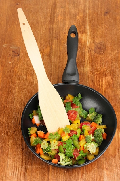 Legumes frescos fatiados na panela na mesa de madeira