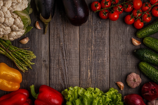 Legumes frescos para cozinhar no escuro de madeira.