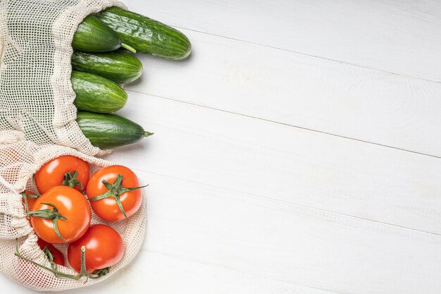 Legumes frescos, tomates e pepinos em sacos ecológicos