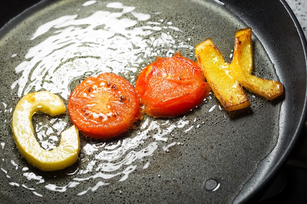 Legumes fritos em forma de letras em uma frigideira no óleo