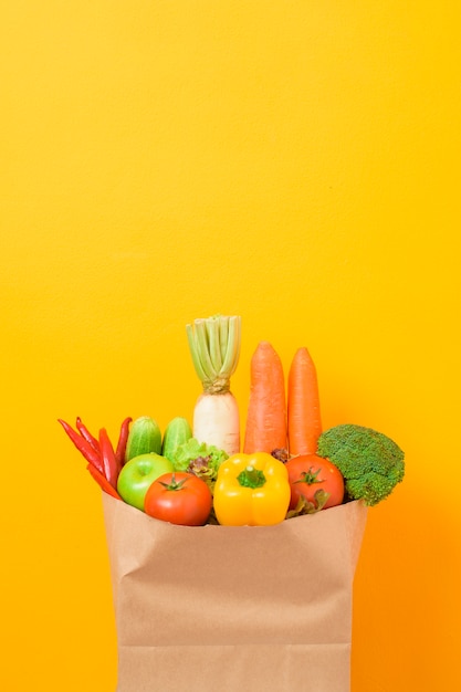 Legumes na sacola de compras na parede amarela