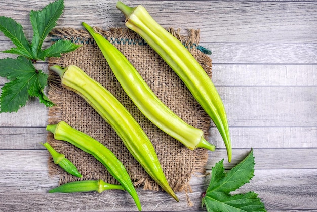 Legumes saudáveis de quiabo verde fresco e okara folha em fundo cinzaVista superior