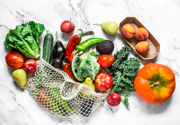 Legumes sazonais em um fundo de mármore couve repolho abobrinha berinjela pimenta couve-flor tomate abóbora e peras maçãs pêssegos Vista superior