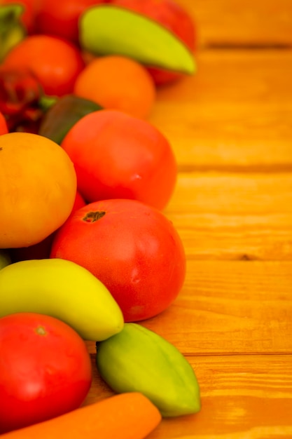 Legumes suculentos maduros brilhantes em uma mesa de madeira tomates cebolas cenouras páprica pimentão copie o foco seletivo do espaço