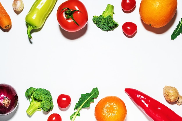 Legumes variados e frutas na superfície branca.