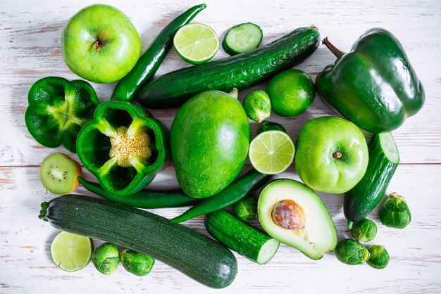 Legumes verdes e frutas em fundo branco de madeira cortados pela metade. slides. visão aérea