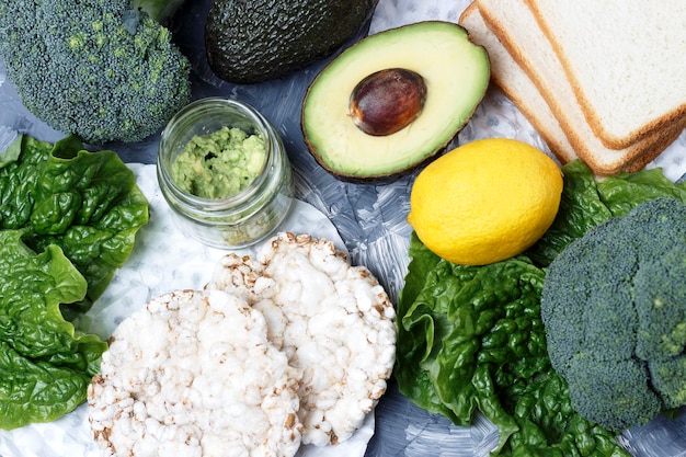 Legumes verdes e pão no conceito de comida saudável de vista superior de fundo cinza