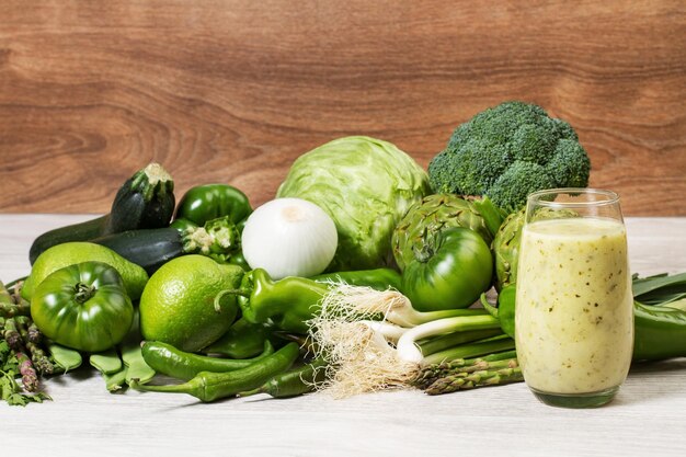 Legumes verdes e uma bebida saudável em uma mesa de madeira