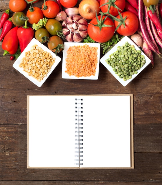 Foto leguminosas em tigelas e legumes em uma mesa de madeira com notebook