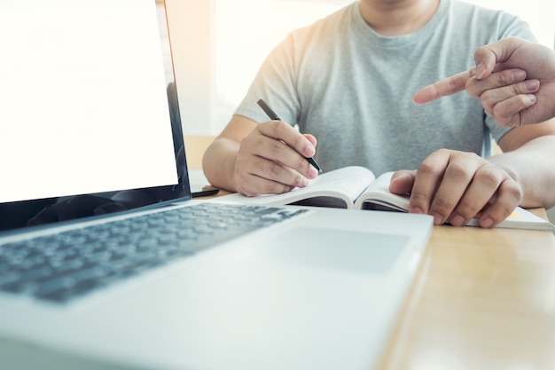 Foto lehre helfen technologie-konzept. frau junge lehrer oder tutor mit erwachsenen studenten im klassenzimmer am schreibtisch mit papieren, laptop-computer. studiengang