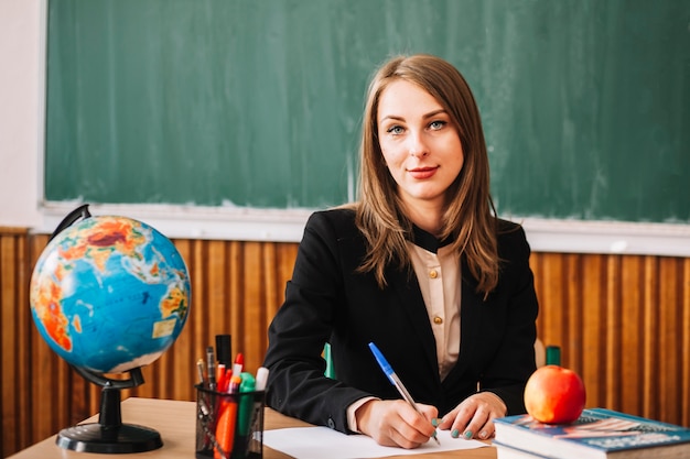 Lehrer, der Kamera beim Sitzen am Schreibtisch betrachtet