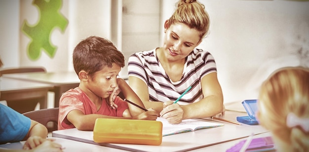 Foto lehrer hilft kindern bei den hausaufgaben im klassenzimmer