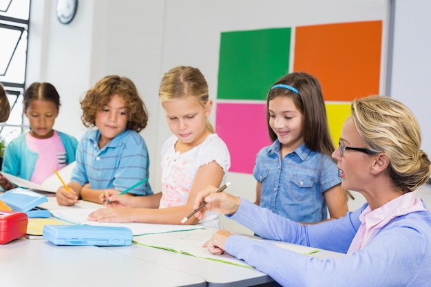 Lehrer hilft Kindern bei ihren Hausaufgaben im Klassenzimmer