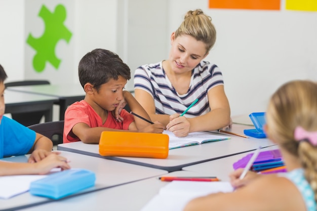 Lehrer hilft Kindern bei ihren Hausaufgaben im Klassenzimmer