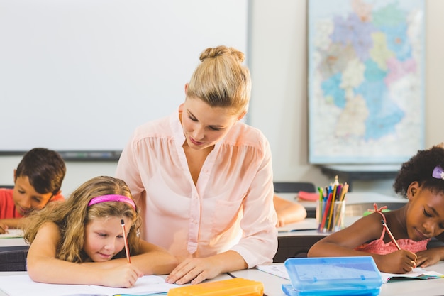 Lehrer hilft Kindern bei ihren Hausaufgaben im Klassenzimmer