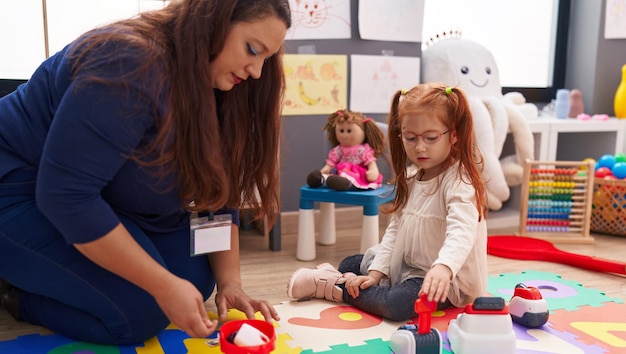 Foto lehrer und schüler spielen ein supermarktspiel, das im kindergarten auf dem boden sitzt