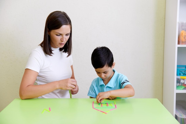 Lehrer und Vorschulkind bauen Haus auf einem Tisch