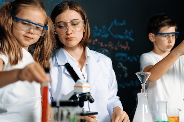 Foto lehrer unterstützen studenten, flüssigkeit in einer röhre im labor zu experimentieren.