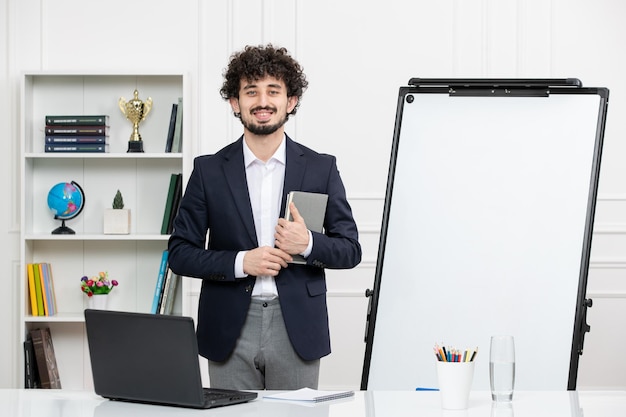 Lehrerin, brünette Ausbilderin mit Computer im Anzug und Whiteboard-Klassenzimmer, lächelnd im Stehen