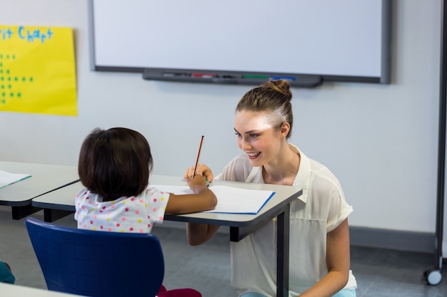 Lehrerin kniet durch Schulmädchen