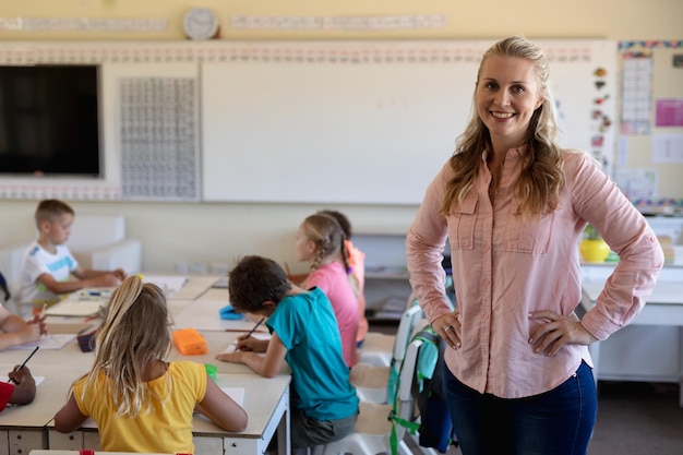 Lehrerin mit langen blonden Haaren steht in einem Klassenzimmer