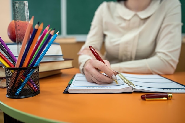 Lehrerin sitzt an einem Tisch mit Büchern und Heften