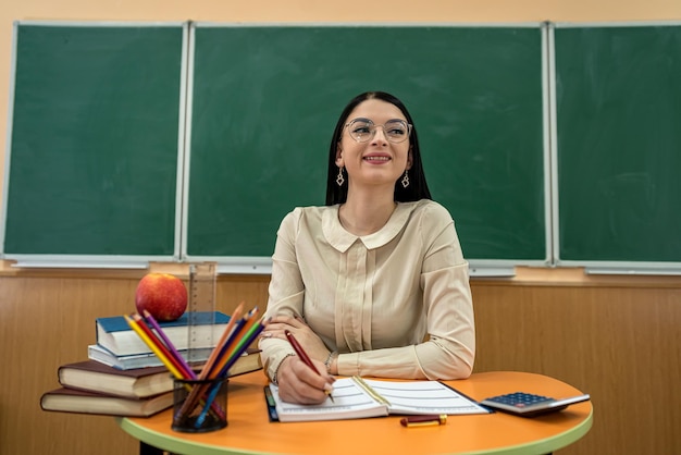 Lehrerin sitzt an einem Tisch mit Büchern und Heften