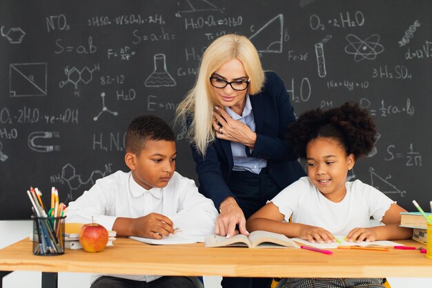 Lehrerin unterrichtet Schulkinder, die an einem Schreibtisch sitzen und Probleme lösen