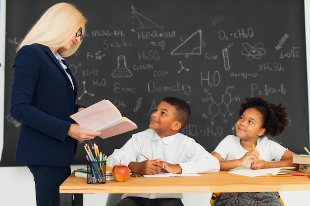 Lehrerin unterrichtet Schulkinder, die an einem Schreibtisch sitzen und Probleme lösen