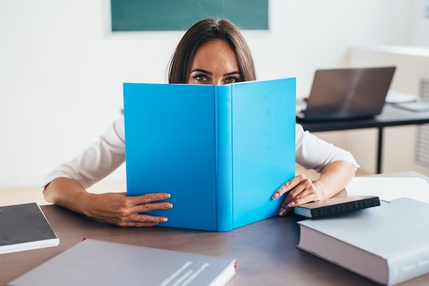 Lehrerin versteckt Gesicht hinter Buch