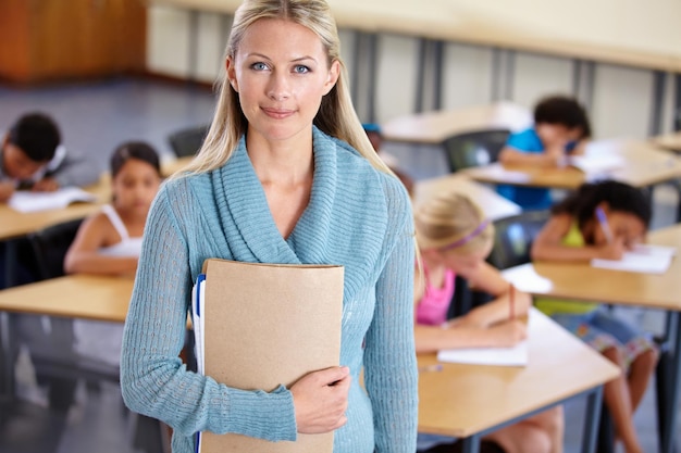 Lehrerporträt und Frau mit Ordner im Klassenzimmer der Grundschule oder Klasse. Bildungsunterricht und weibliche Erzieherin mit Ordnerunterlagen oder Dokumenten für ernsthaftes Wissenslernen oder Studium